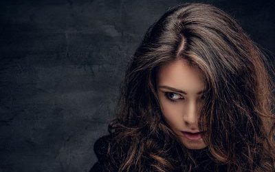 Portrait of sensual brunette female with long curly hair dressed in warm black pullover.